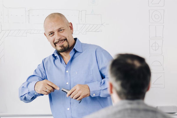 Toleranzen und ISO-GPS Referent steht vor einem Whiteboard mit Blick zu den Teilnehmern